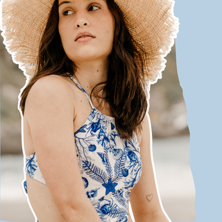 woman wearing straw sunhat and white bathing suit with blue seashell pattern
